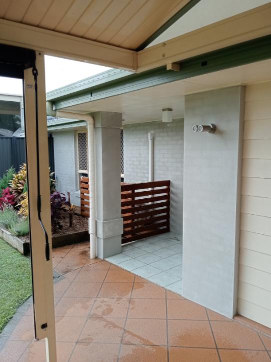 Rendered patio column and wall beside a timber slat gate