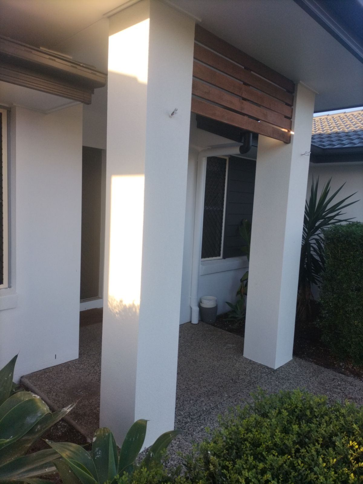 Smooth white rendered entry columns under a timber slat feature