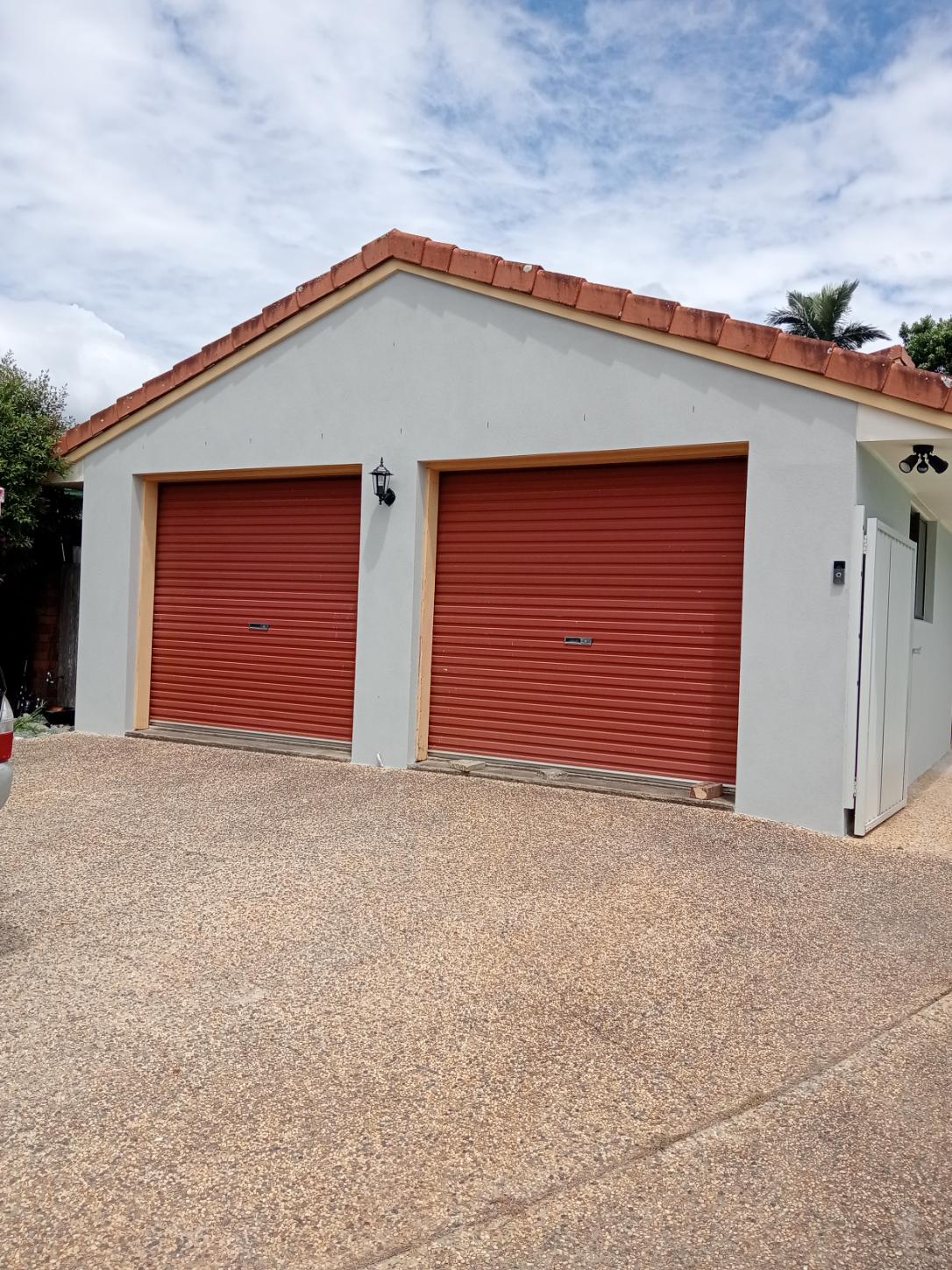 Double garage with a grey rendered gable end under terracotta roof tiles