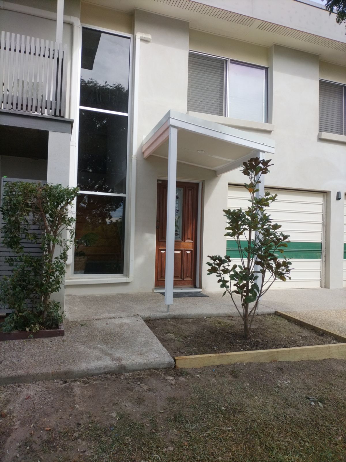 Two-storey house front with a smooth rendered facade and timber front door